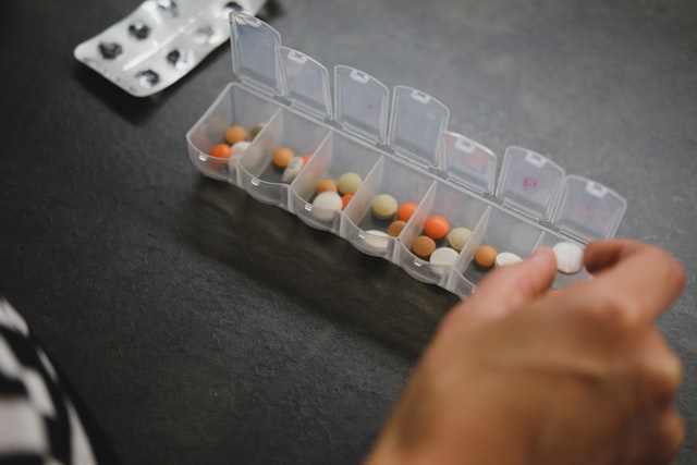 Person putting pills into a weekly medical planning storage device